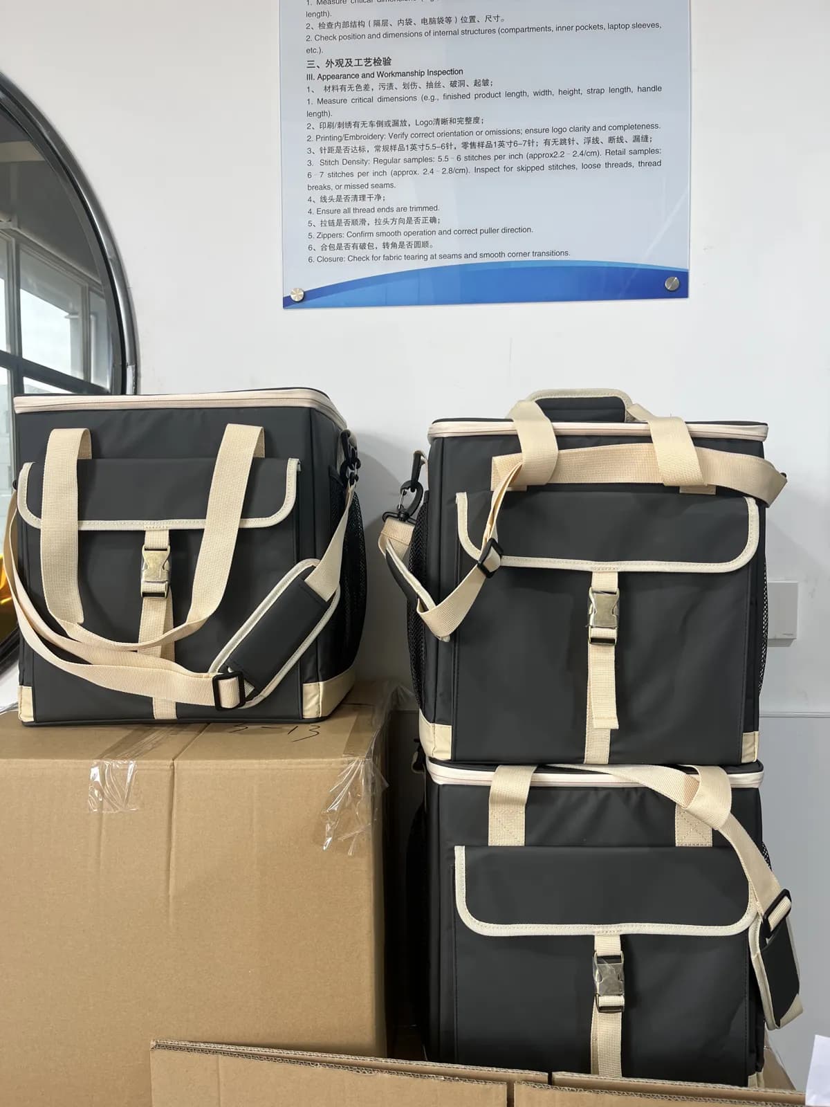 Stacked private label cooler bags with beige handles and front pockets in the factory